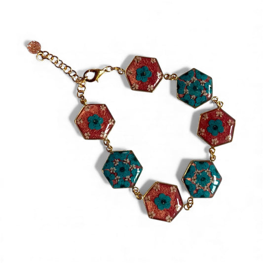 Gold Colored Bracelet with Teal Plum Blossoms, pieces of Queen Anne’s Lace in a Coral Pink Background